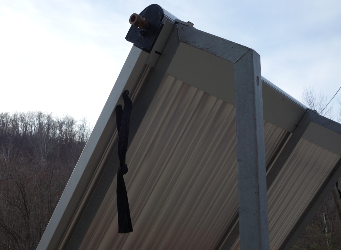 Top rear view of the CPC1518 solar collector with the optional horizontal roof mounting kit. The black strap seen hanging under the collector is to aid in lifting the collector during handling and installation. The mounting frame is attached to the solar collector at the top near the manifold with a small bracket.